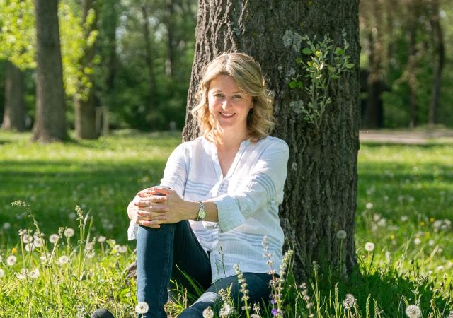 Birgit sitzend an Baum angelehnt im Aubad Tulln